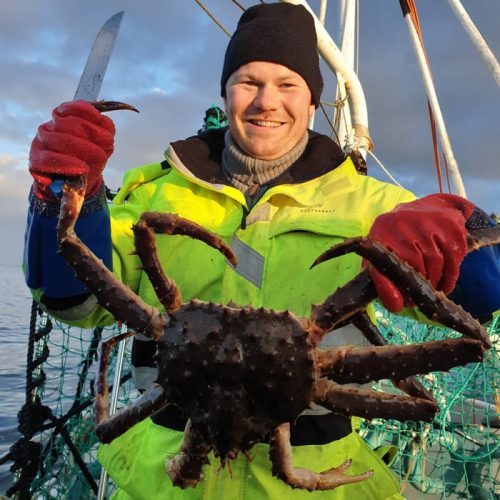male guest holding king crab wearing yellow suit