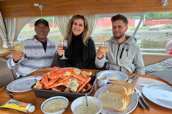 Smiling guests eating freshly caught king crab on boat